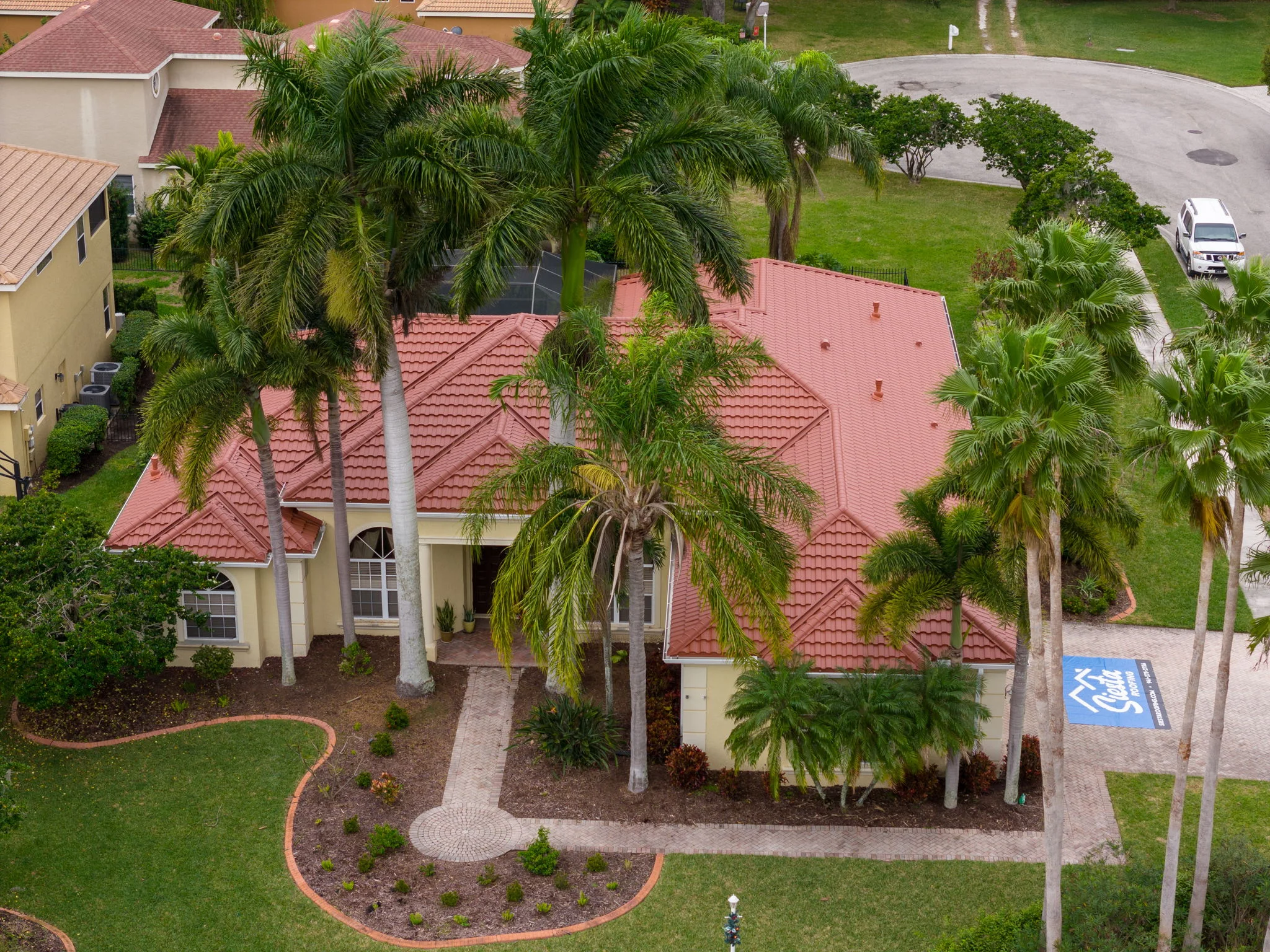 Aerial photo of a house with a terracotta red metal tile roof.
