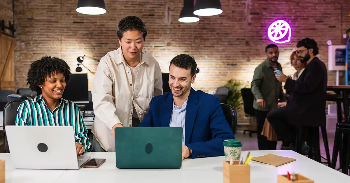 Equipe de pequenas e médias empresas trabalhando em laptops em um escritório moderno, representando estratégias de assessoria de imprensa acessíveis e eficazes.