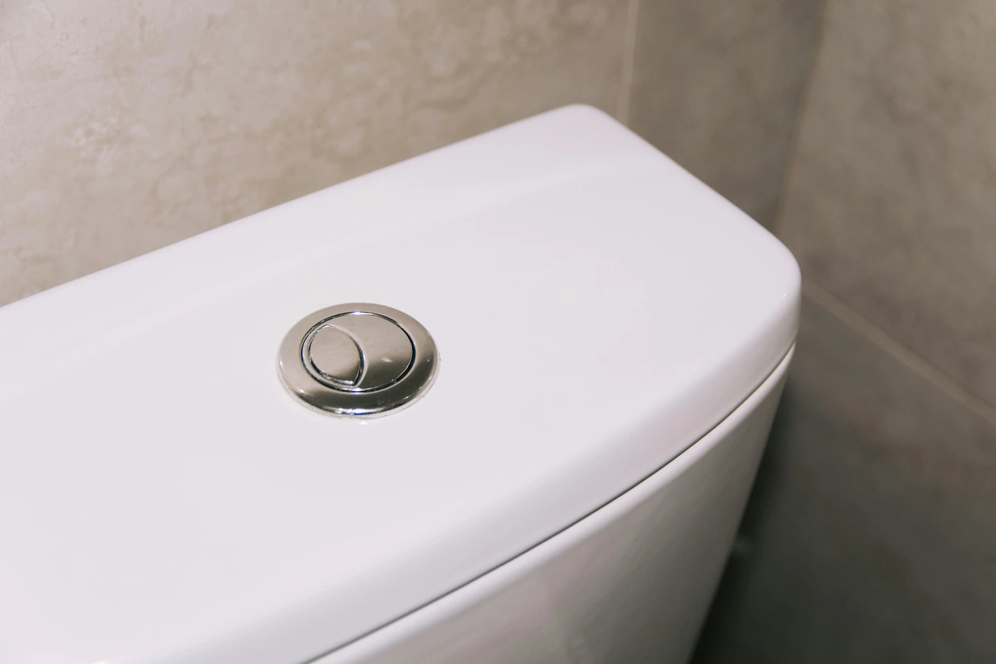 bouton poussoir d'un mécanisme de chasse d'eau WC sur un réservoir de toilettes
