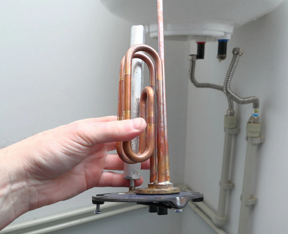 Main tenant une résistance chauffante électrique pour cumulus, vue rapprochée