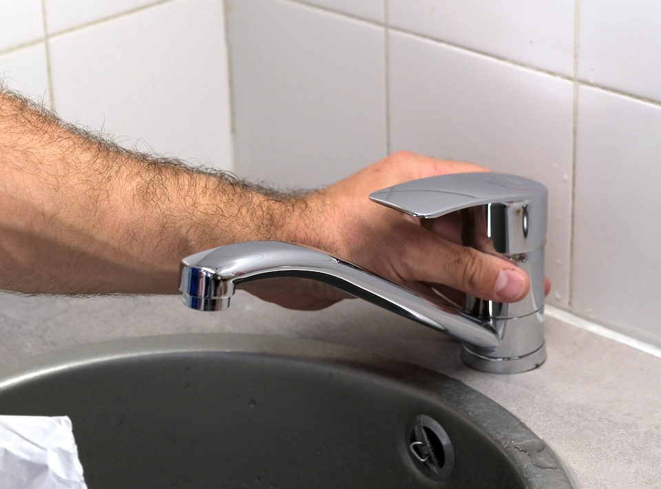 Homme en t-shirt bleu réparant des toilettes, dépannage professionnel plomberie
