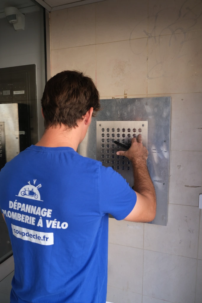 plombier en t-shirt bleu réparant des toilettes, dépannage professionnel plomberie