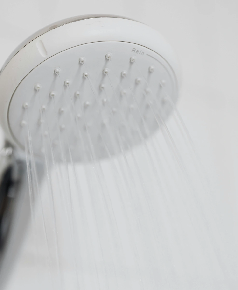Pommeau de douche blanc diffusant un jet d'eau en mode pluie.