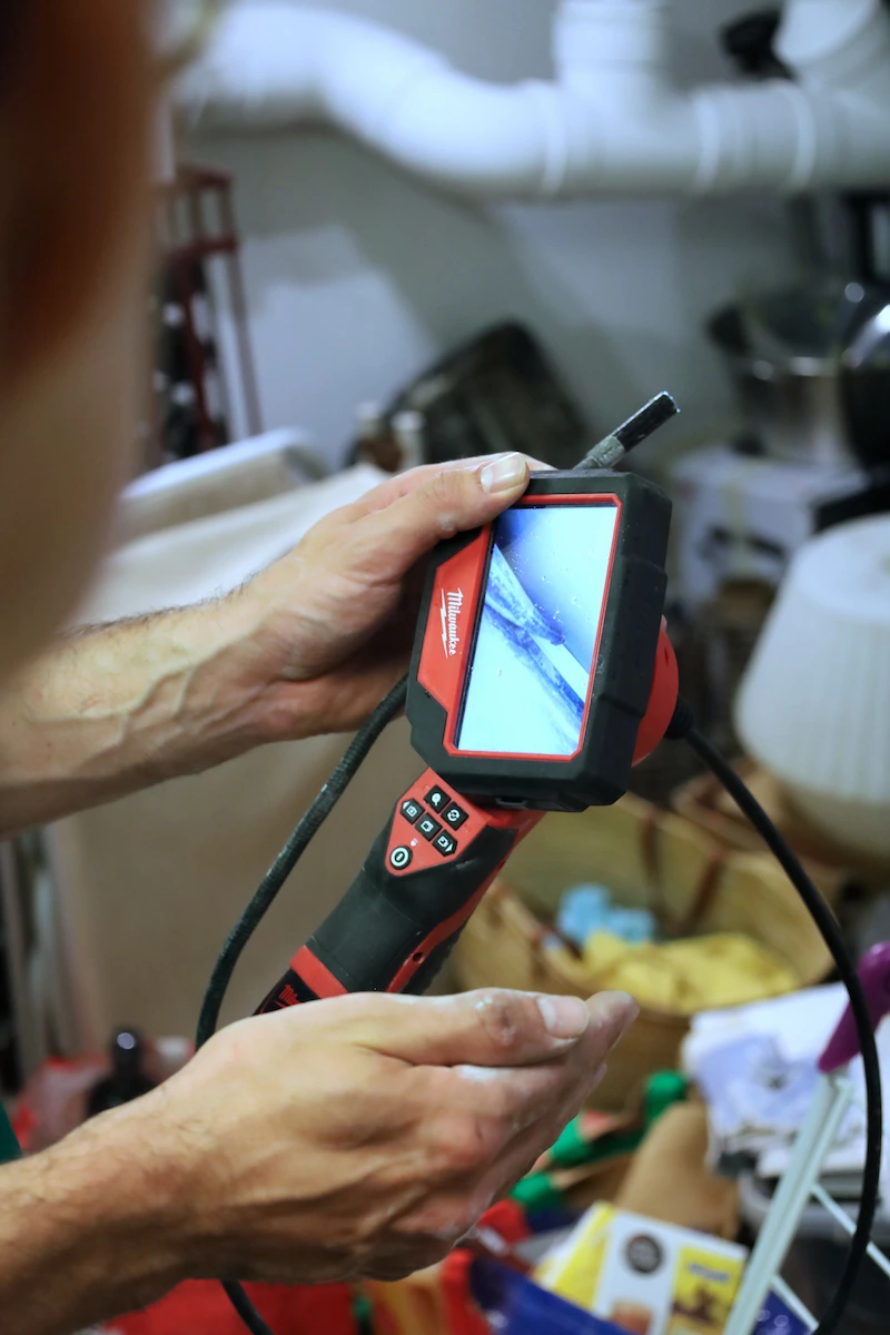 Personne tenant une caméra d'inspection endoscopique Milwaukee utilisée pour rechercher des fuites dans des tuyaux.