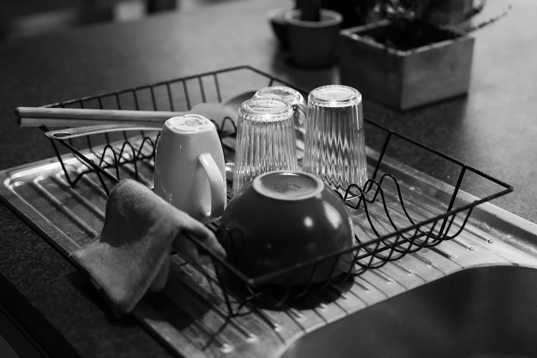 Égouttoir avec mugs, bols, verres retournés et baguettes au-dessus de l'évier de cuisine.