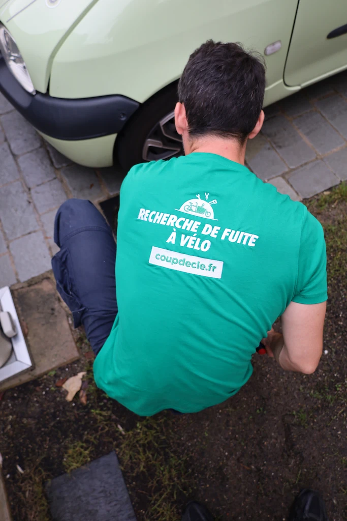 Plombier portant une t-shirt bleu réparant le mécanisme d'un WC suspendu