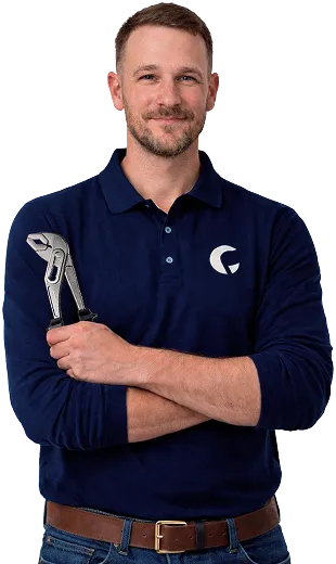 Homme souriant en polo bleu marine tenant une pince-clé, bras croisés.