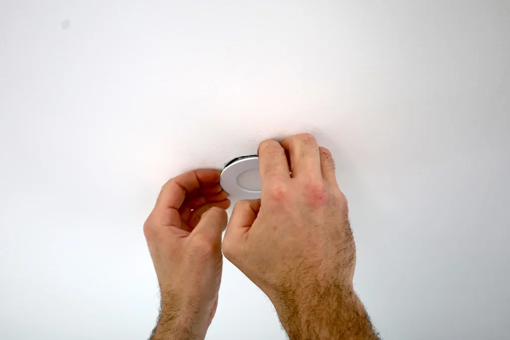 Technicien électricien remplaçant un spot luminaire encastré à Bordeaux.