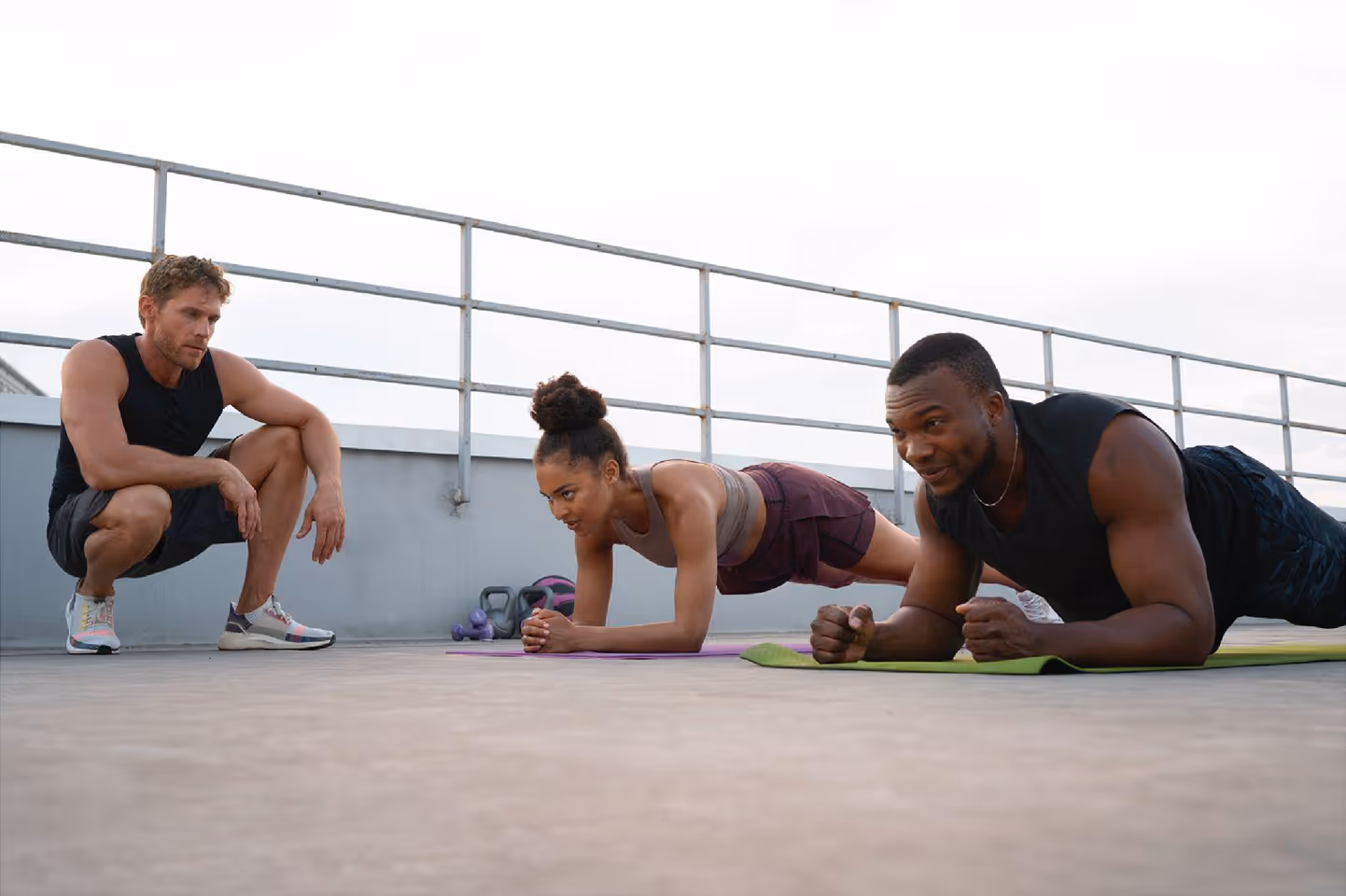 Coaching sportif professionnel en présentiel : collaborateurs en position de gainage supervisés par un entraîneur expert.