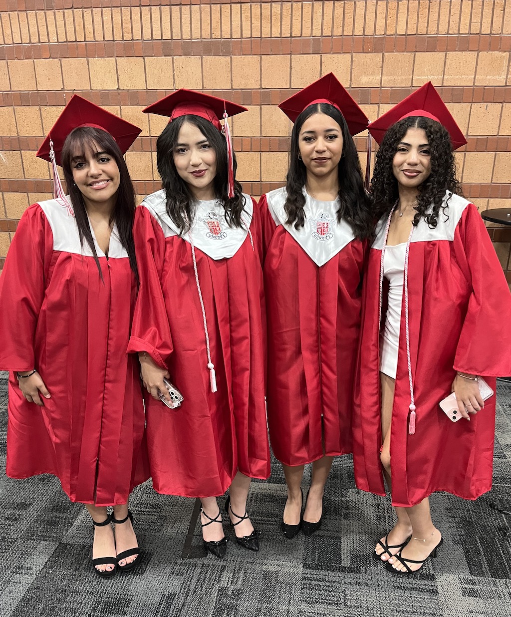 Latina students in red graduation gowns and caps