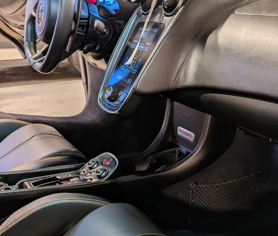 The interior of a car with a steering wheel and a remote control.