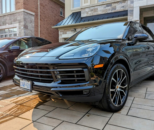 A black porsche cayen is parked in front of a house.
