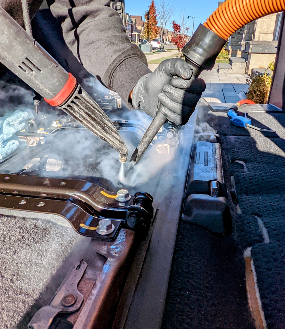 A man is using a blow gun on a piece of metal.