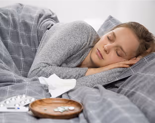 Person holding a credit card and using a white tablet displaying a financial website with the text 'Your money works' and a cup of tea nearby.