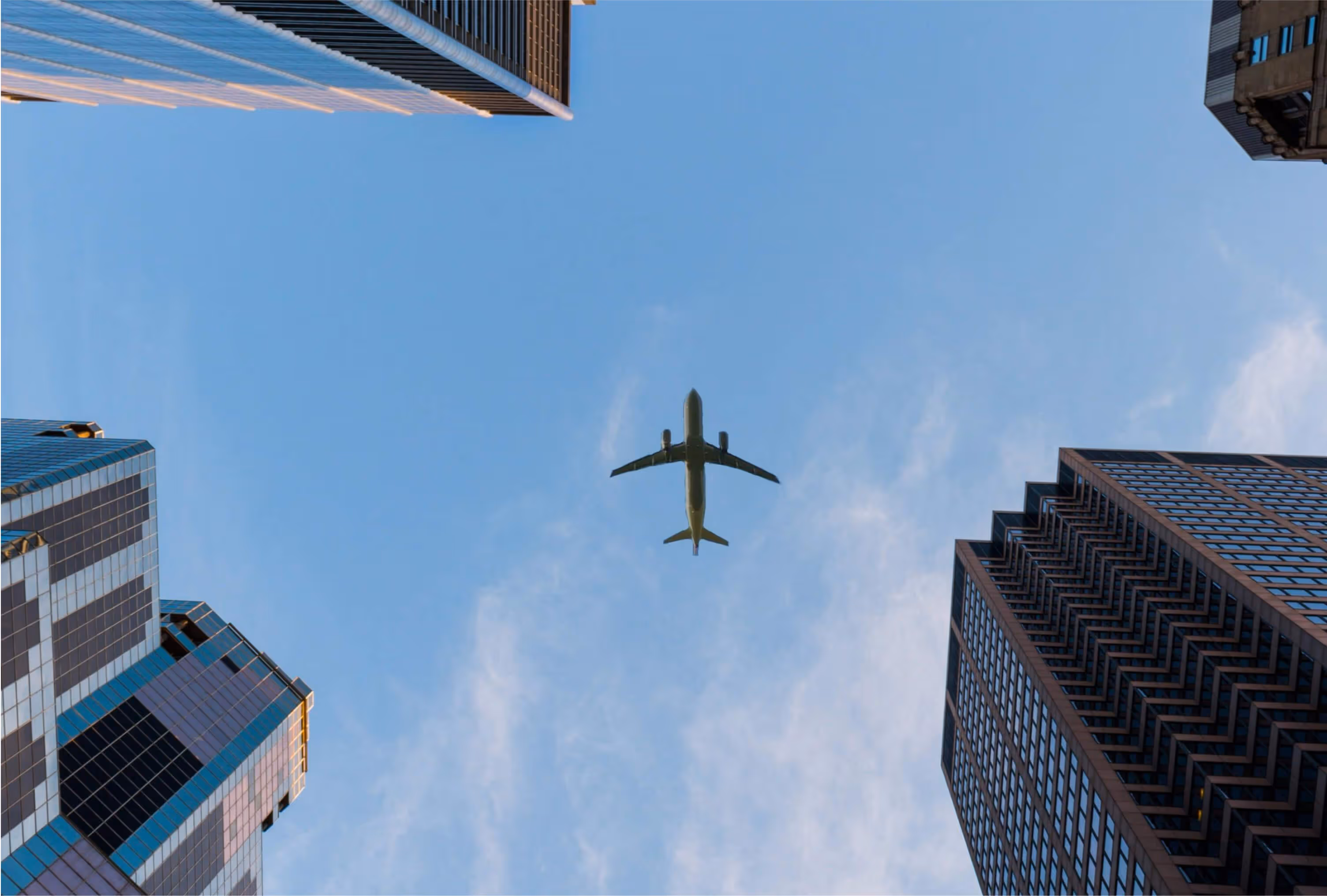 An airplane flying in the sky between two buildings.