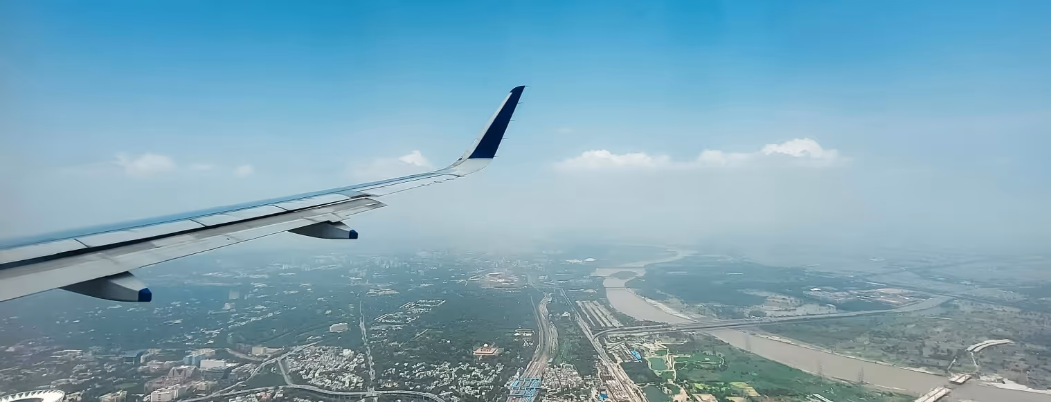 A view of the wing of an airplane flying over a city.