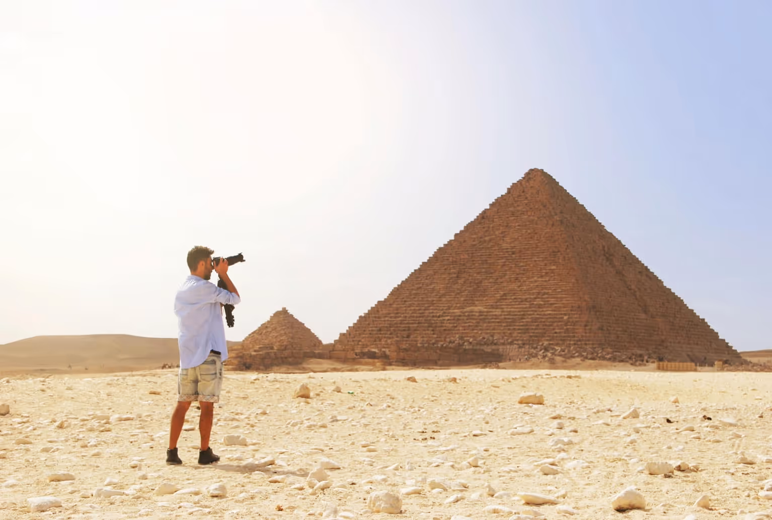 A man taking a picture of the pyramids of giza.