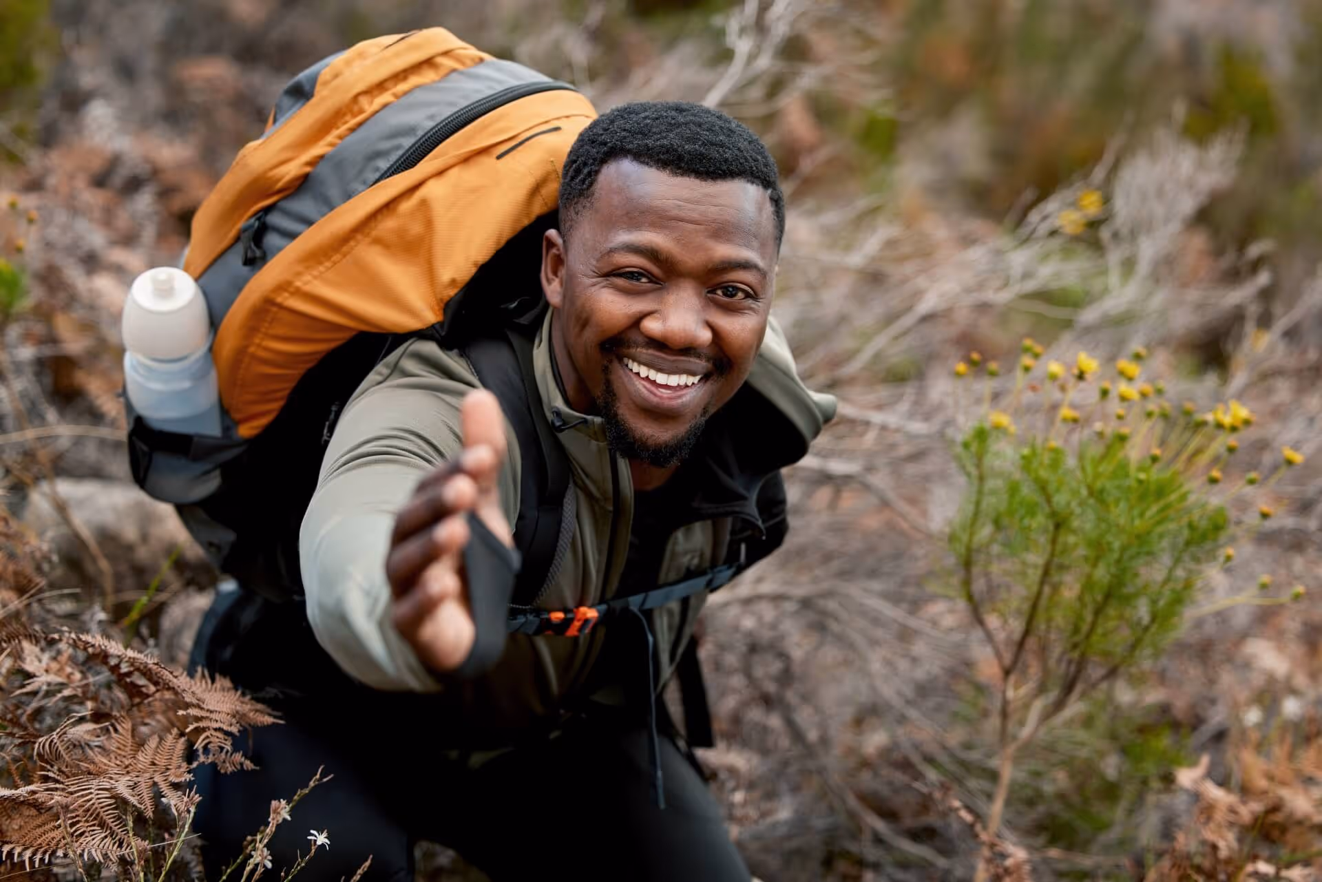man climbing mountain asking help with his hand out stretched