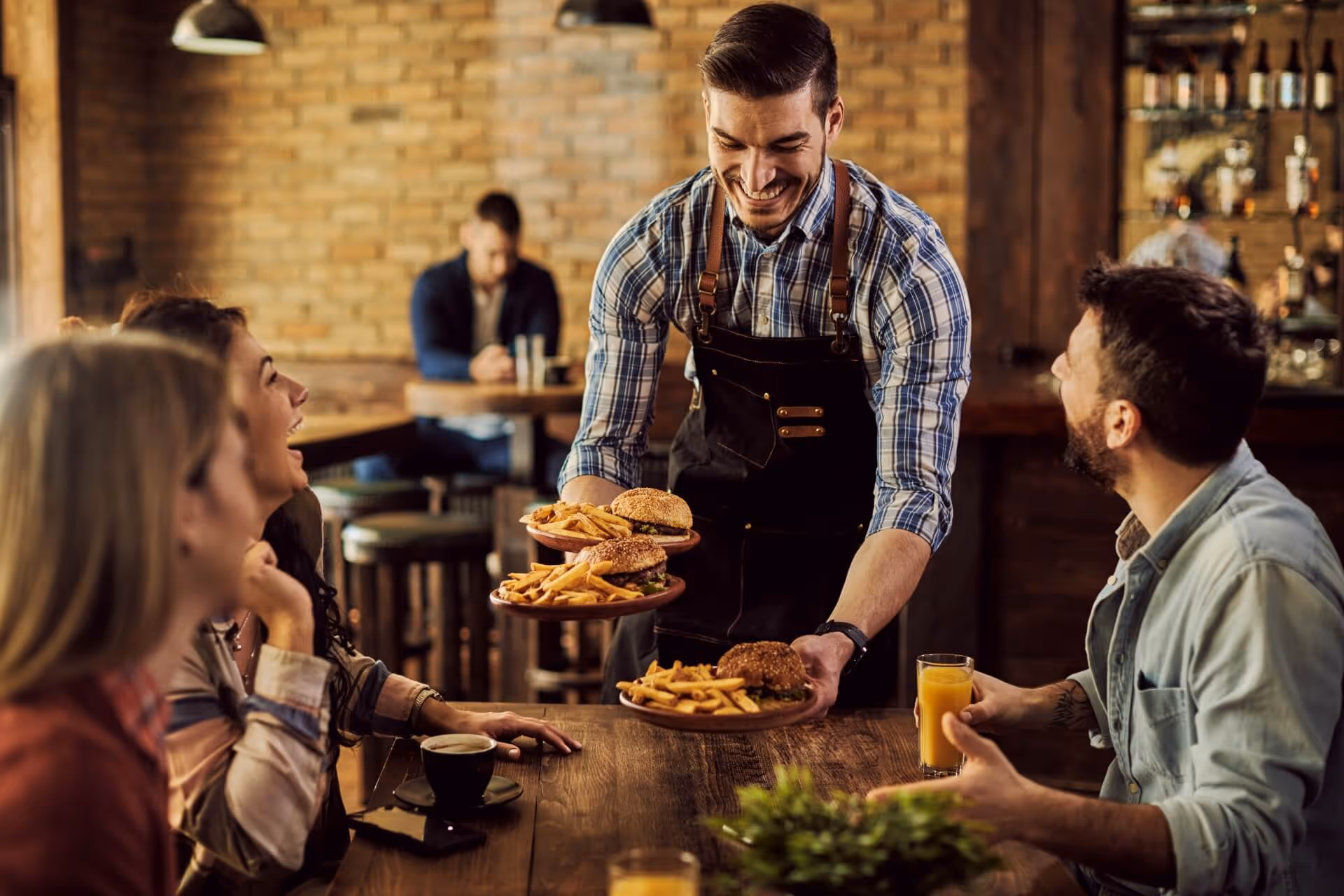 waiter serving food to group of friends