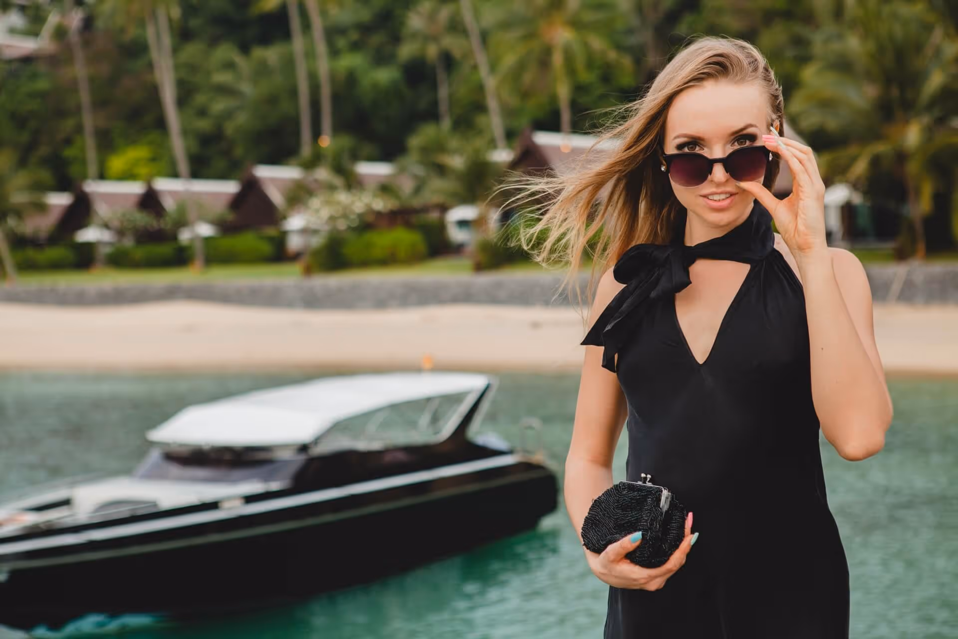 woman dressed in black dress posing on pier in luxury resort hotel