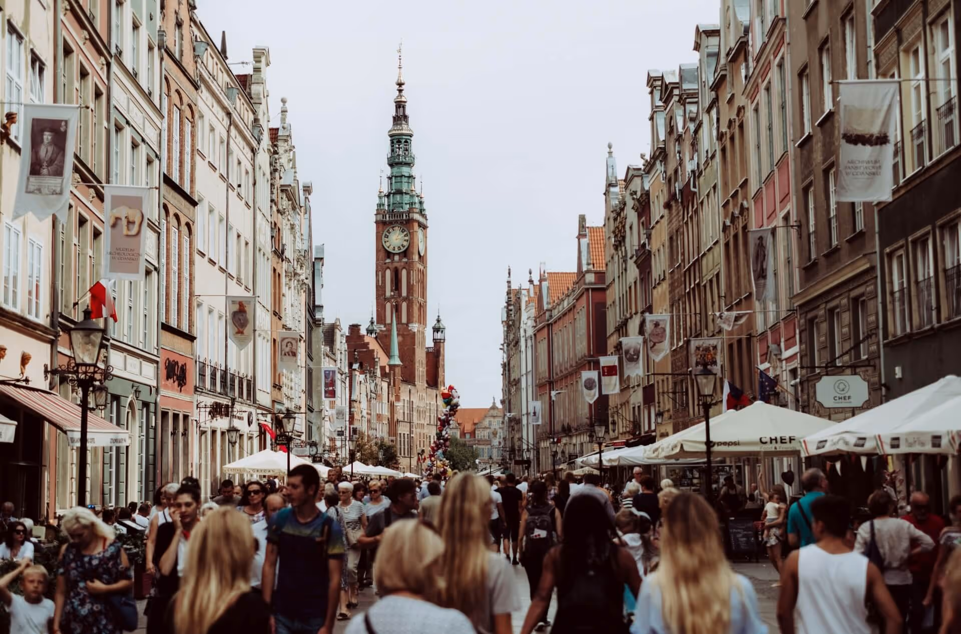 street with people and brown clock tower n background