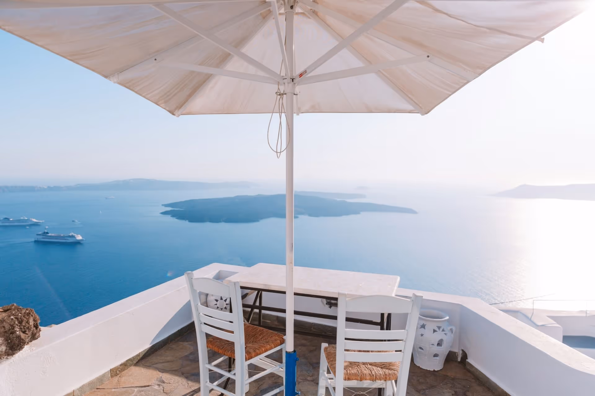 An umbrella shades a table overlooking the sea