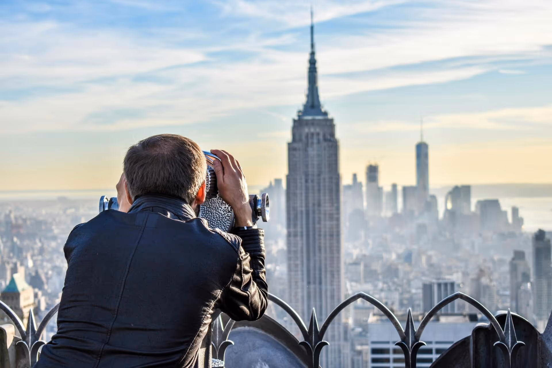 Man looking through binoculars at new york city skyline