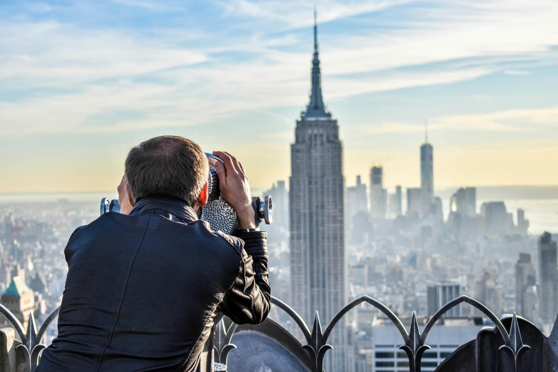 Man looking through binoculars at new york city skyline