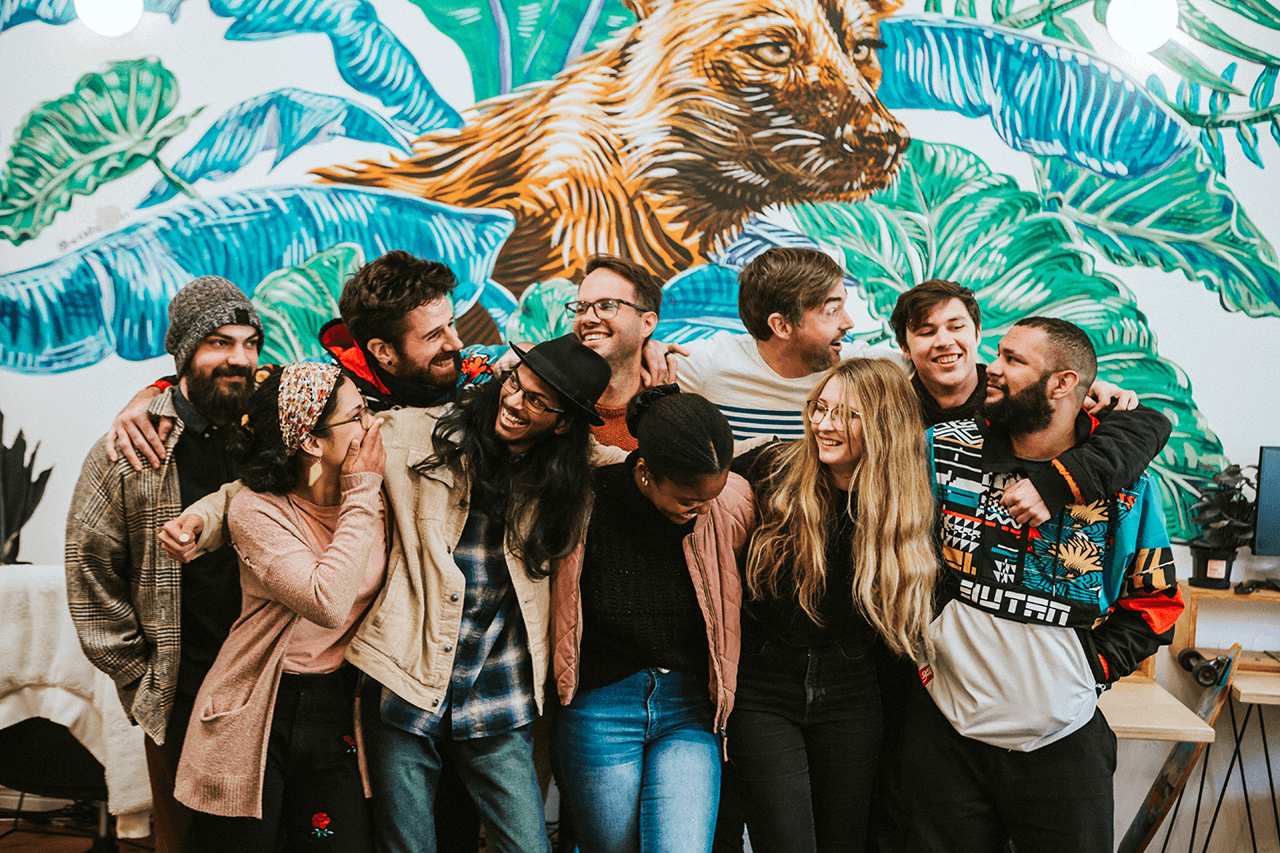 Photo of the Studio Bo team standing in their office in front of a mural of a wild dog.