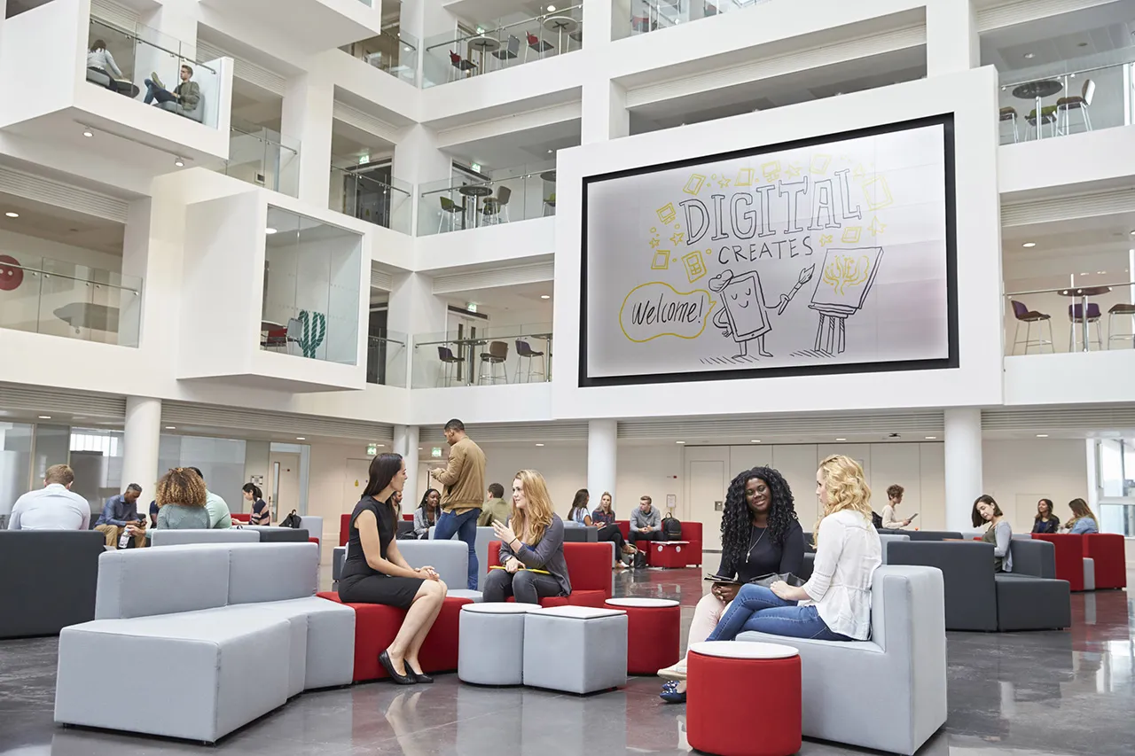 Lively open office space with an illustration on a large screen saying "Digital Creates"