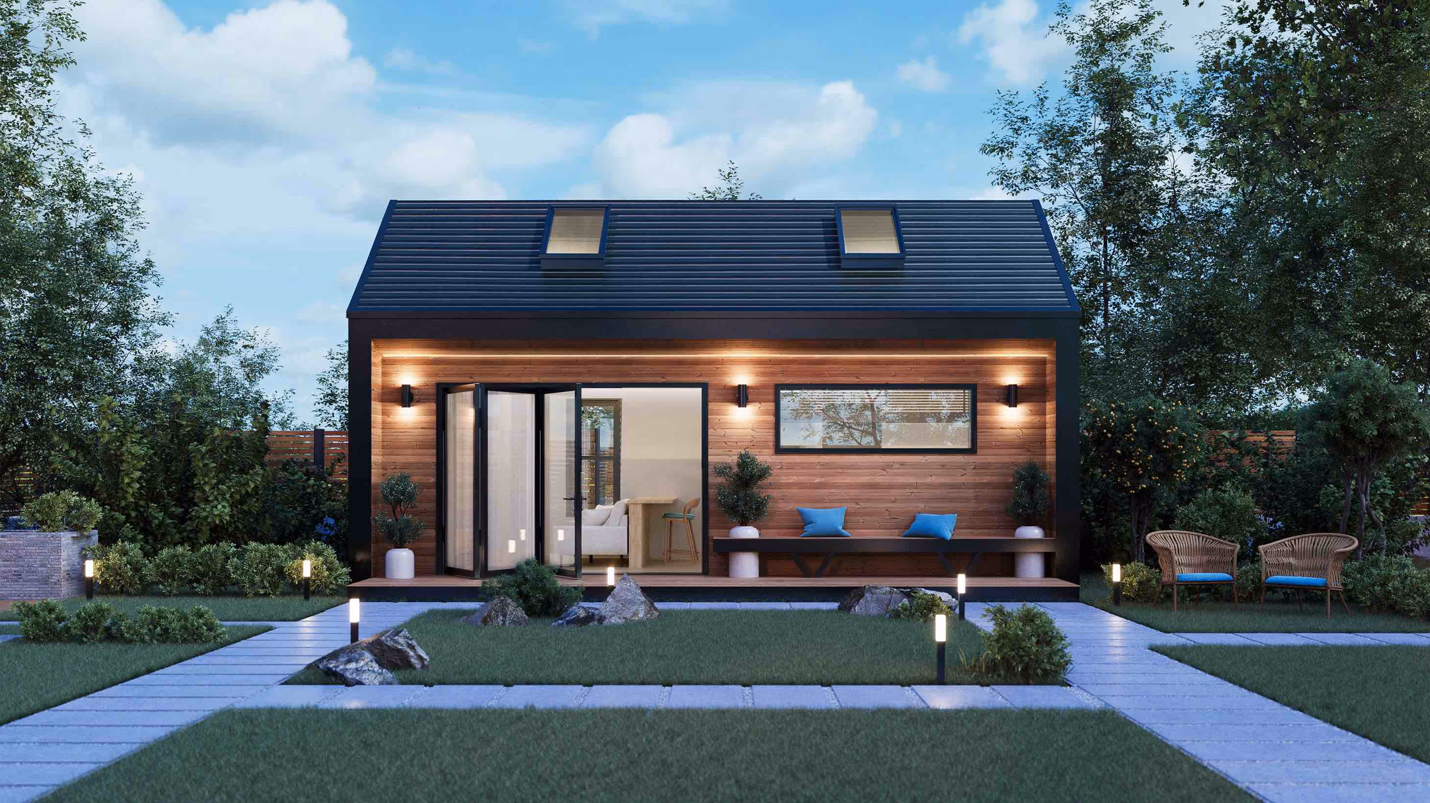Night view of modern prefab accessory dwelling unit - with lights turned on, pitched roof with skylights and deck