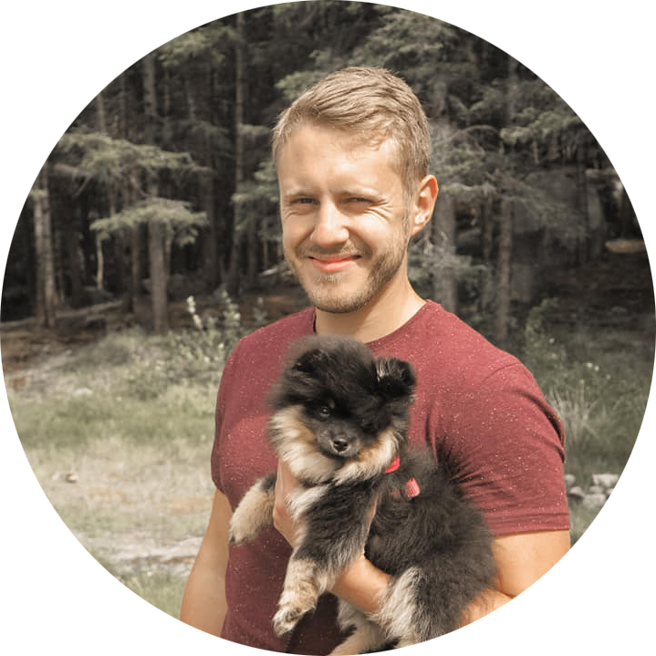 Christer Lende smiling in the woods while holding a puppy