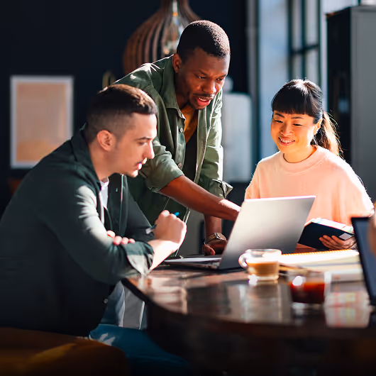 Trois personnes travaillant ensemble autour d’un ordinateur dans un espace de coworking