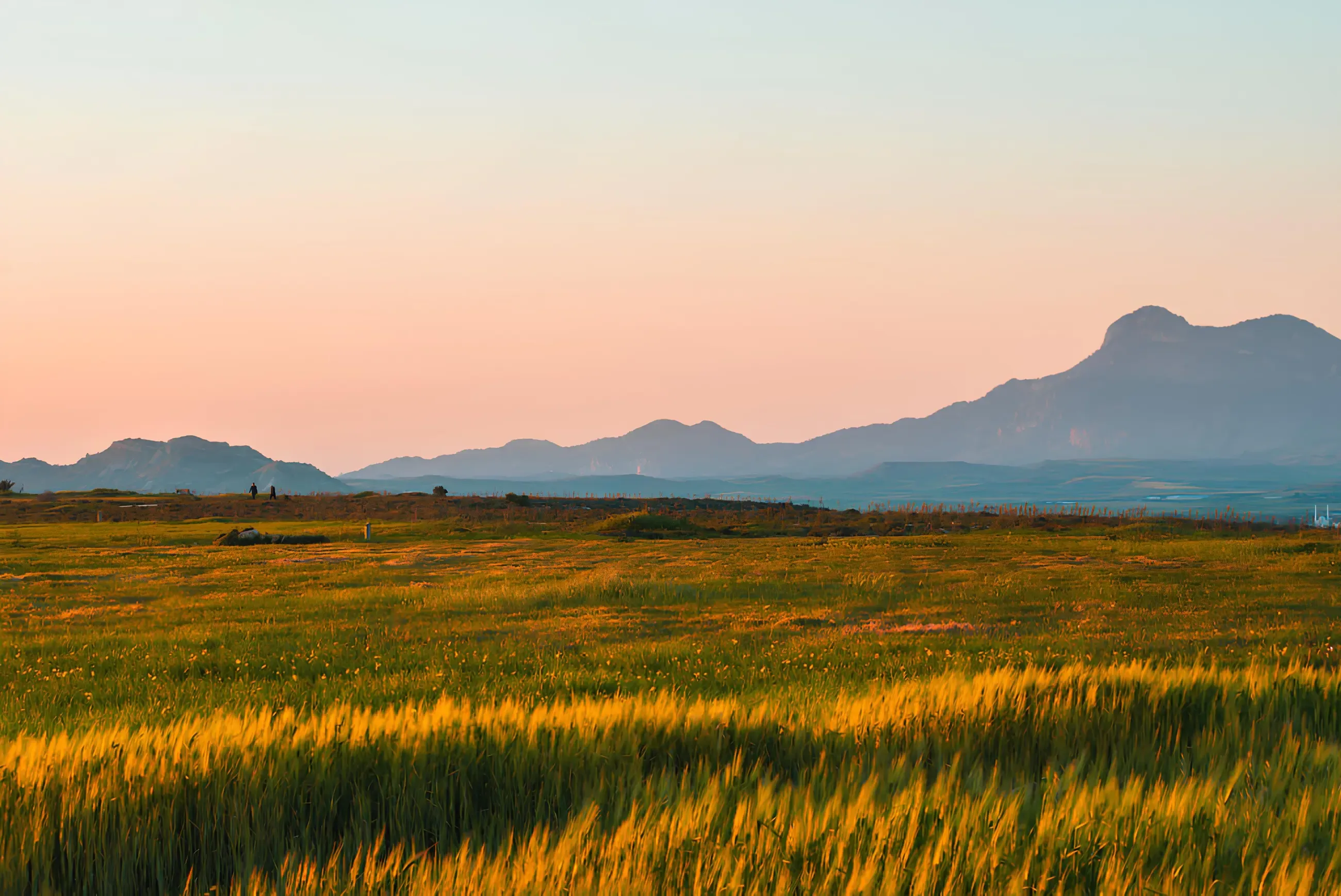 Landscape Field during Sunset with Mountains in the background, with airborne dust in Cyprus creating a hazy sky