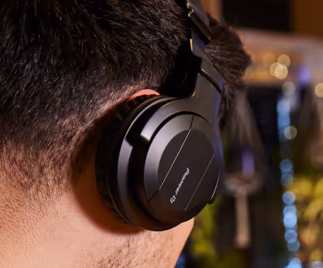 Close-up of a person wearing large black Pioneer DJ headphones, focused on the side of their head and ear.