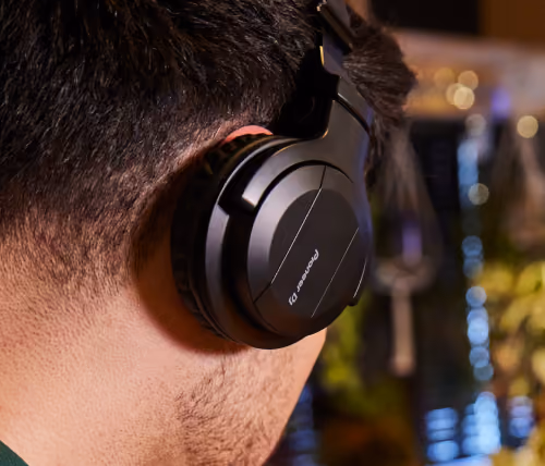 Close-up of a person wearing black Pioneer headphone on their ear with blurred background.