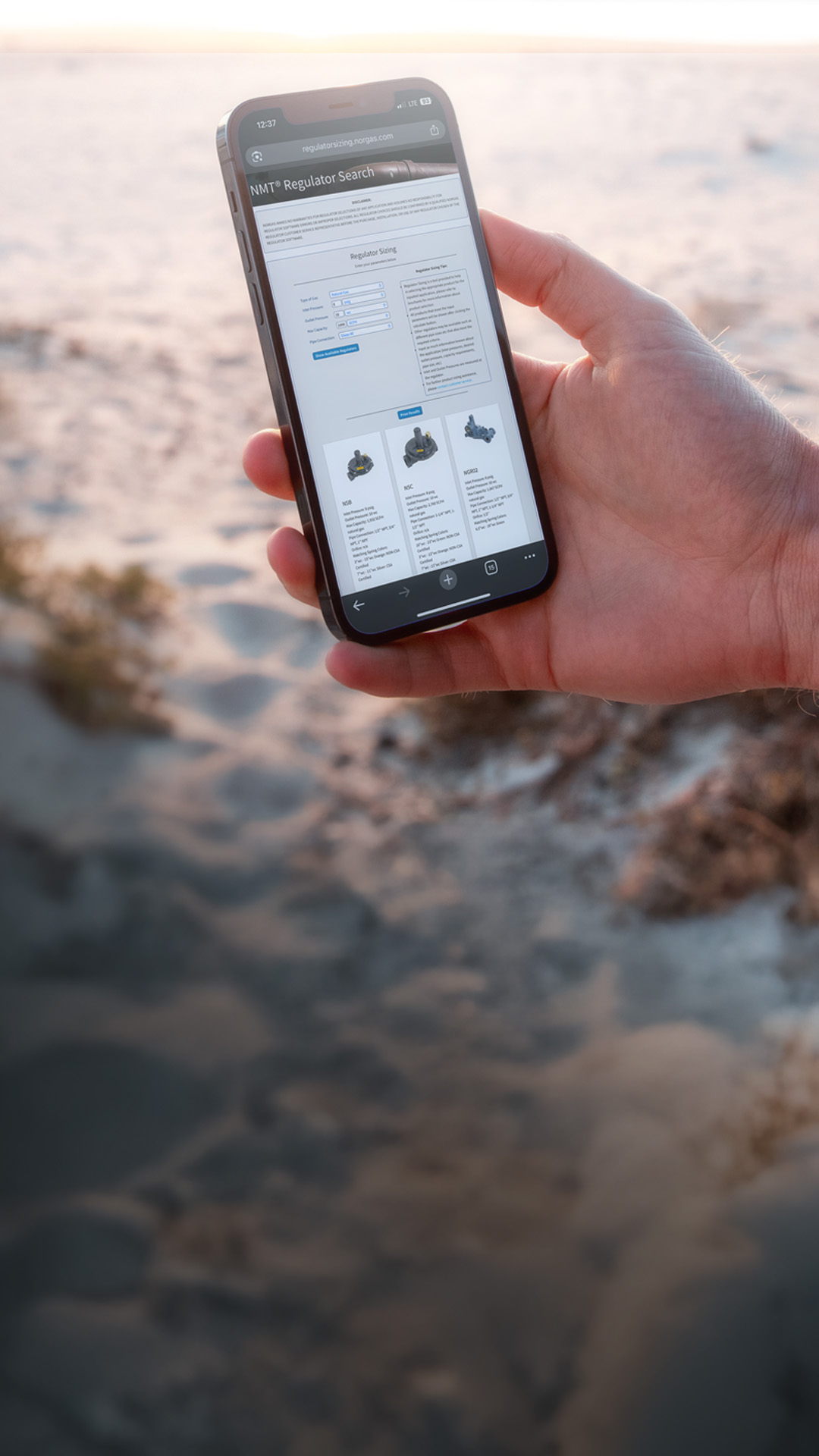 A hand holding a smartphone with the Norgas Regulator Sizing Tool webpage active.