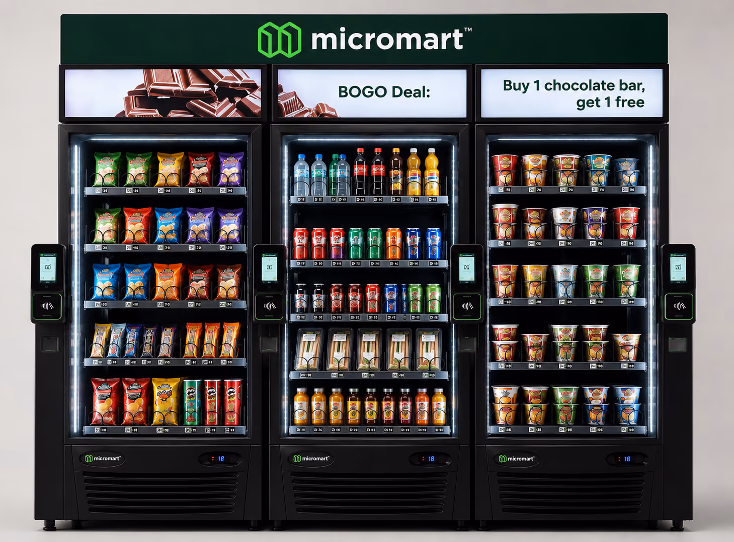 Three micromart vending machines with snacks, drinks, and a buy one get one free chocolate bar sign.