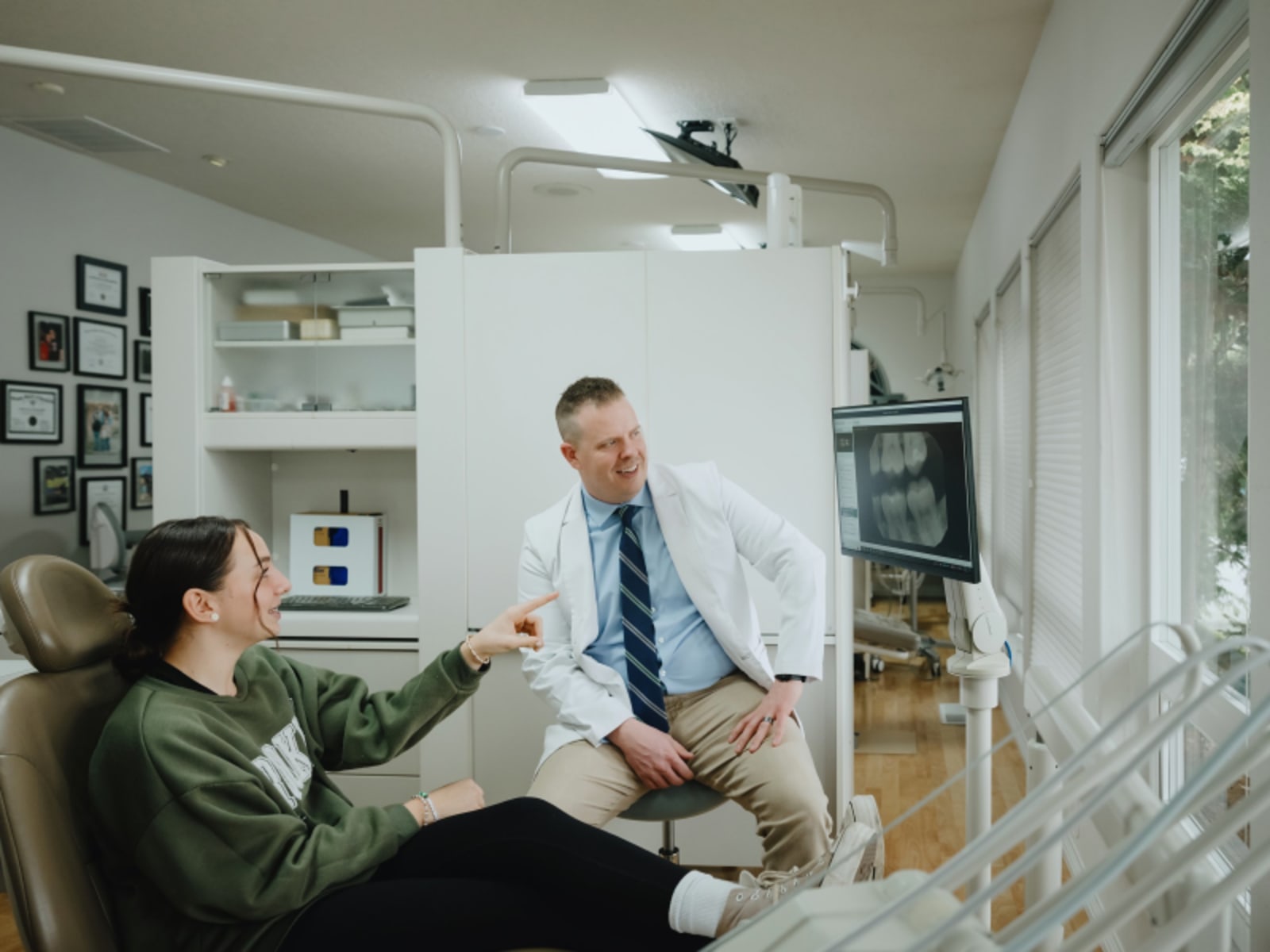 Dentist greeting and making eye contact with young patient in exam room