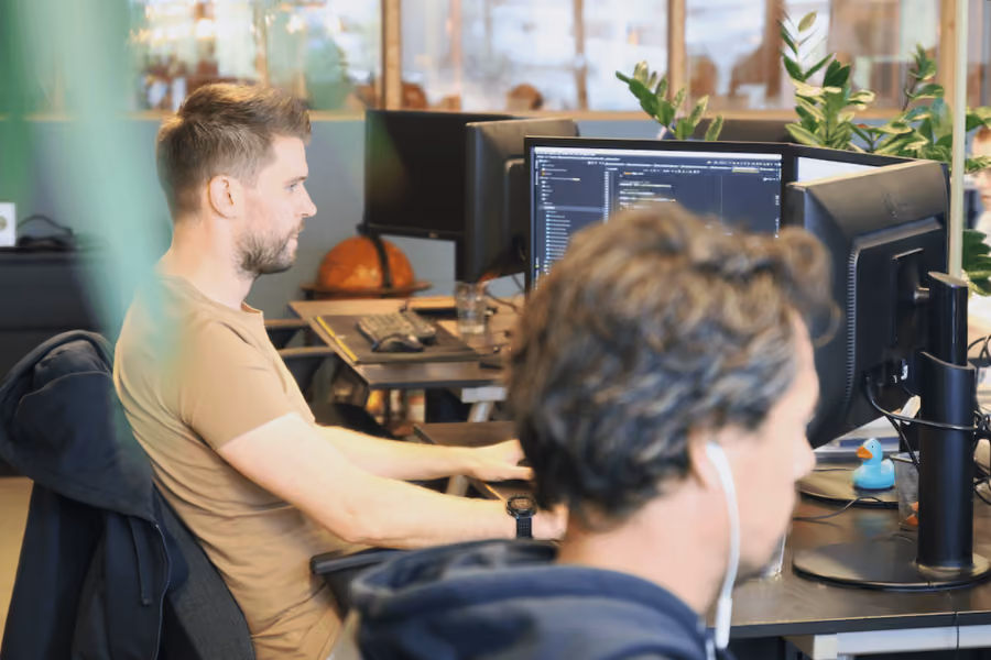 Twee collega's werken samen achter beeldschermen op kantoor
