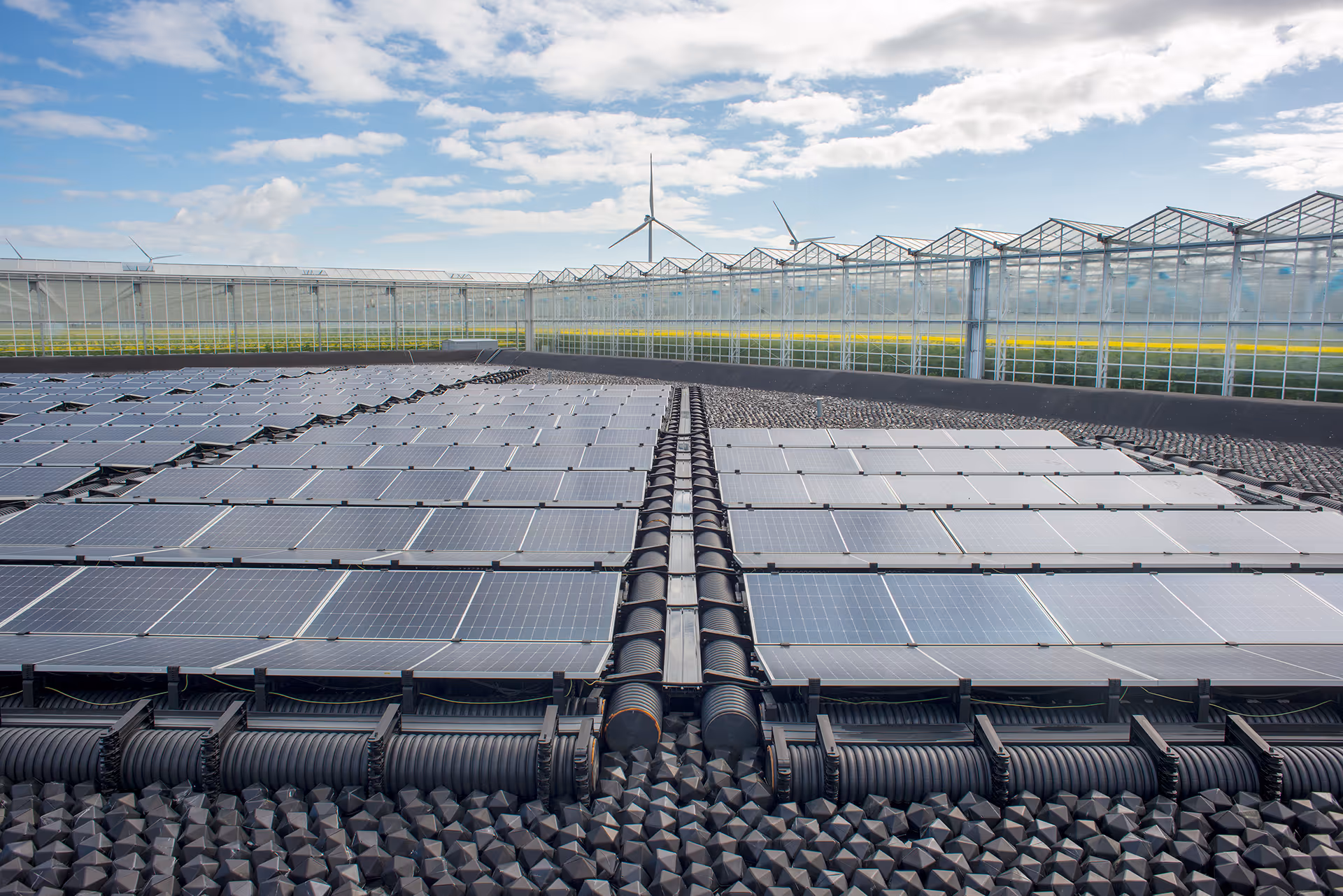 Drijvende zonnepanelen op clickfloats van gerecycleerde fruitkisten in een waterbassin bij de Tomeco serres