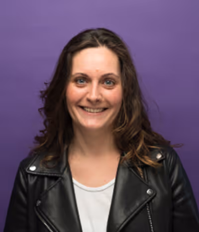 Claire Legay, directrice artistique à l'agence, de face sur un fond mauve, souriante