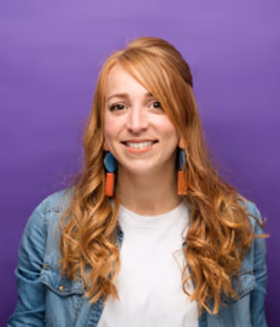 Marion Corre Lemonnier, designer graphique à l'agence, de face sur un fond mauve, souriante