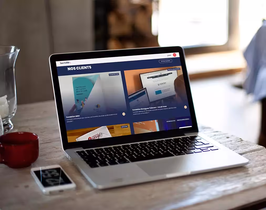 Un ordinateur portable posé sur une table ouvert sur la page d'accueil du site Assemble