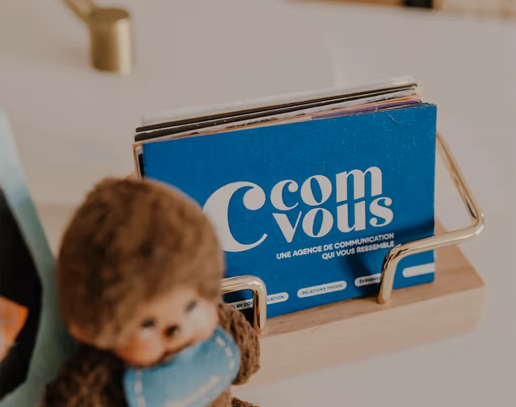 Cartes de visite C’ComVous dans un porte-cartes en bois et laiton, avec logo bleu et slogan imprimé. Cartes de visite C’ComVous dans un porte-cartes en bois et laiton, avec logo bleu et slogan imprimé.