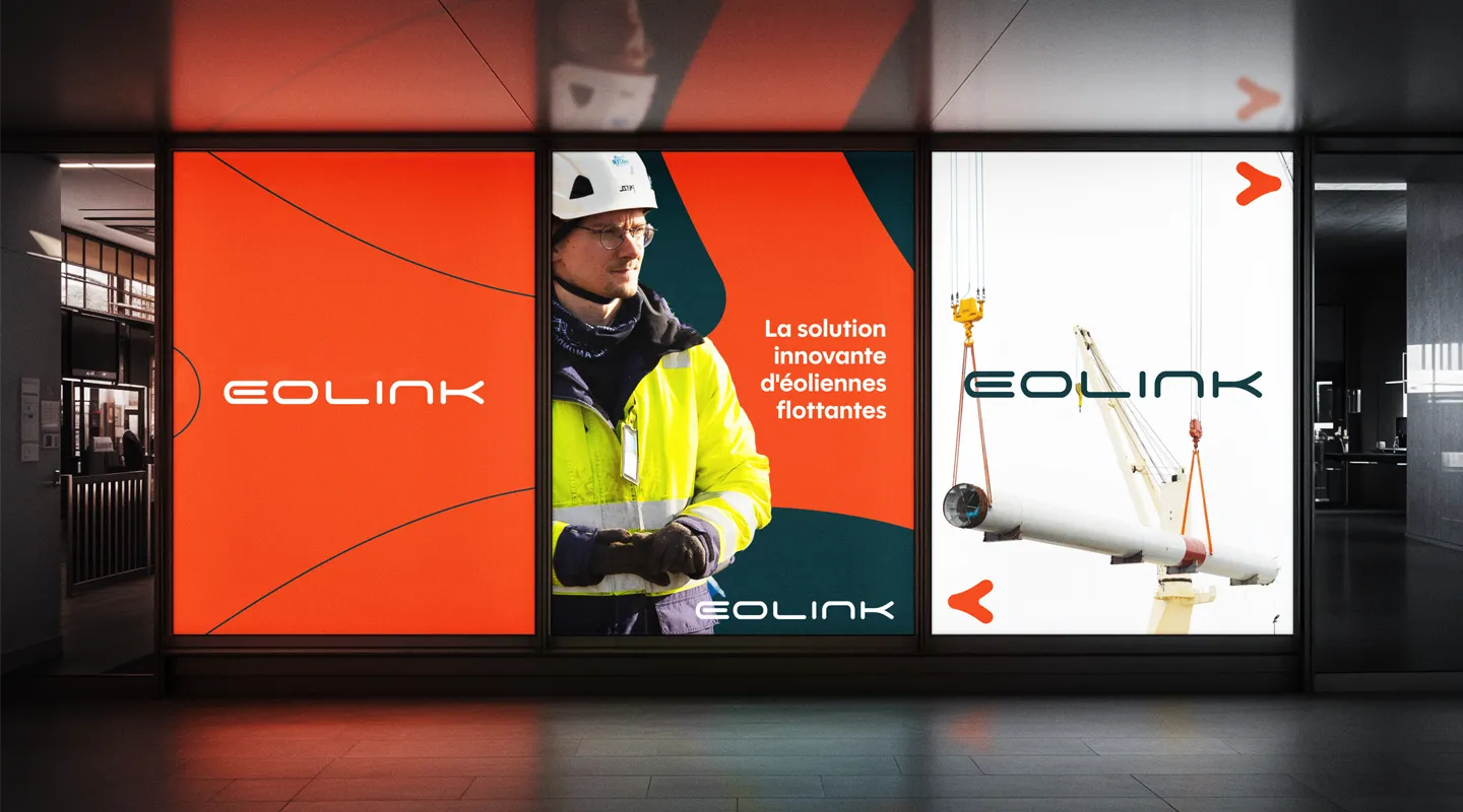 Série d’affiches Eolink en vitrine, avec visuel de technicien, éléments de grue, slogan « La solution innovante d’éoliennes flottantes » et logo de marque.