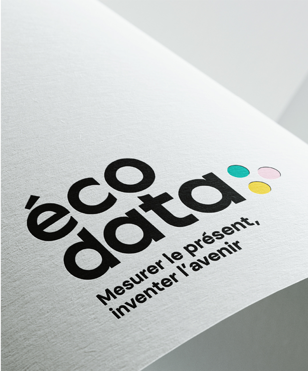 Logo écodata imprimé sur papier, avec le texte « Mesurer le présent, inventer l’avenir » et trois pastilles colorées jaune, rose et turquoise.