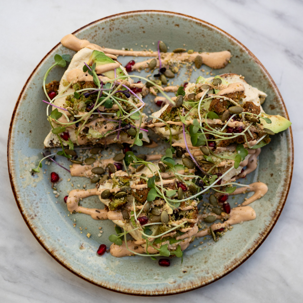 Sourdough toast from Bakery Kultur with hummus, falafel, avocado, pomegranate, dukkah, olive oil and microgreens.
