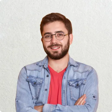 A man Wearing Light blue jacket and red shirt also wearing glasess and a lttle smile on face
