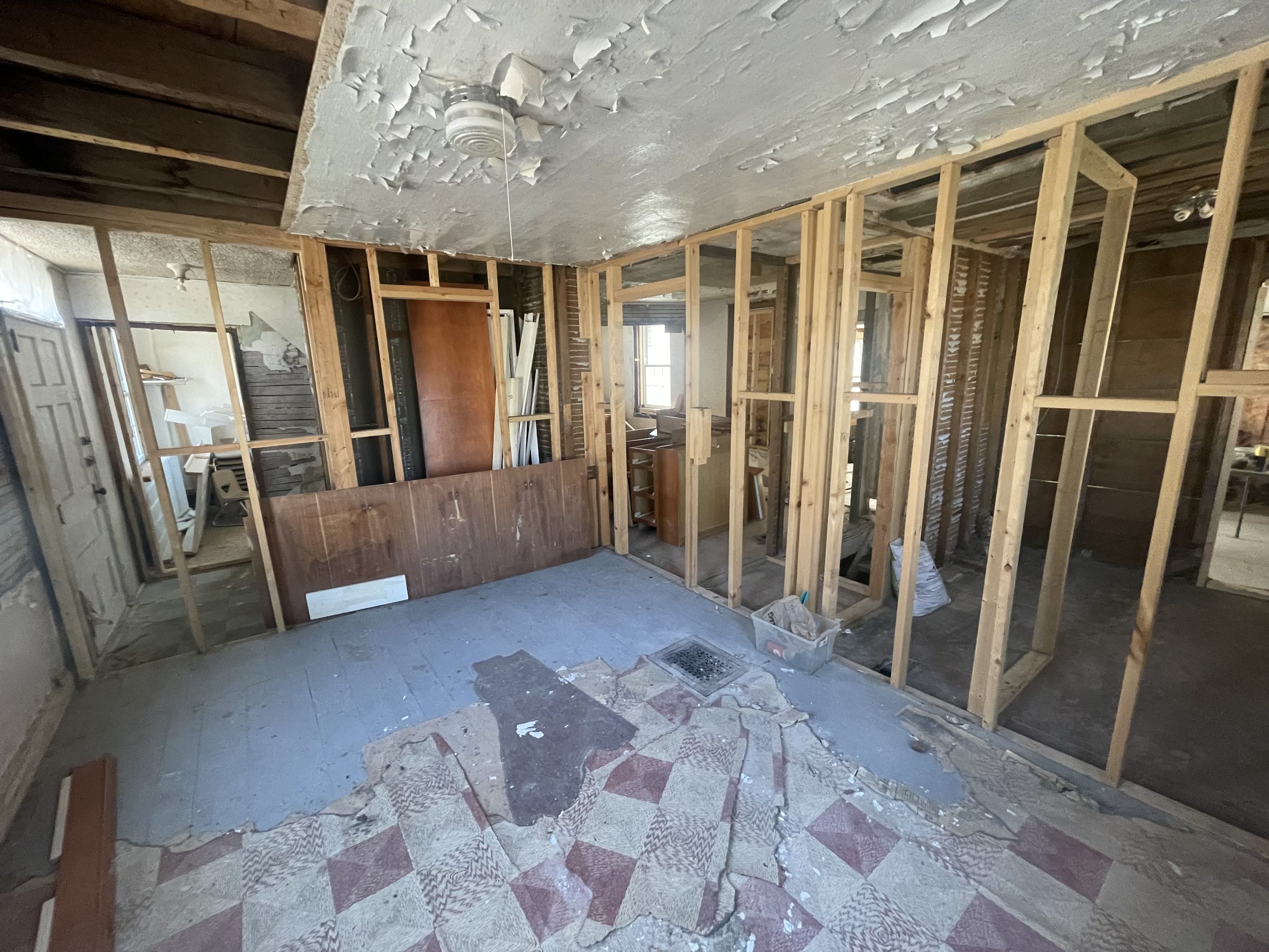 Main floor with partition walls taken back to framing, old checkerboard linoleum still on the subfloor